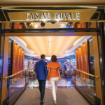 A couple embarking on a lavish casino cruise for their own casino royale experience. by Chasing the Sun Vacations