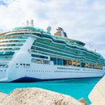 A Travel Advisor observing a large cruise ship docked at a dock. by Chasing the Sun Vacations