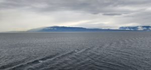 A large body of water with mountains in the background. by Chasing the Sun Vacations