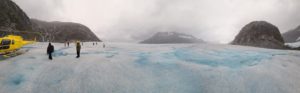 A helicopter sits on top of a glacier with mountains in the background. by Chasing the Sun Vacations