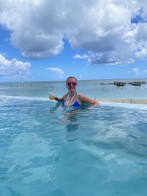 A woman sitting in a pool with a drink in her hand. by Chasing the Sun Vacations