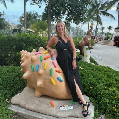 A woman posing next to a statue of a shell. by Chasing the Sun Vacations